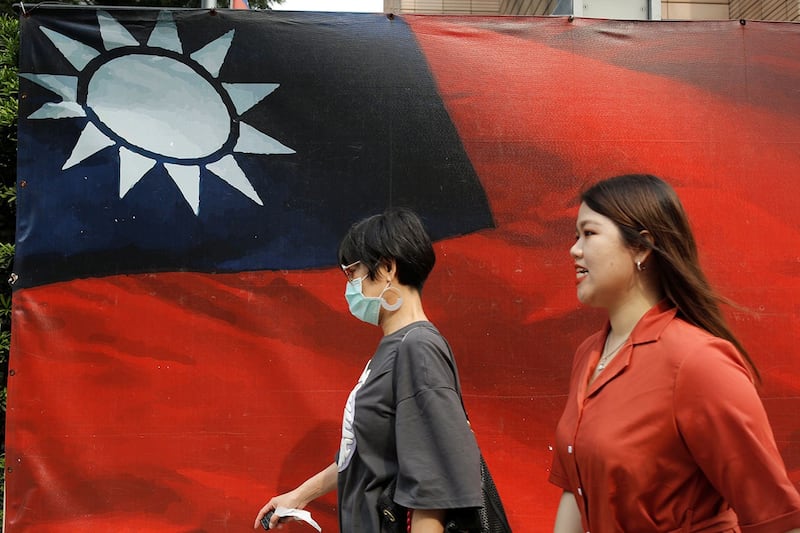 图为从台湾旗帜前走过的行人(路透社)